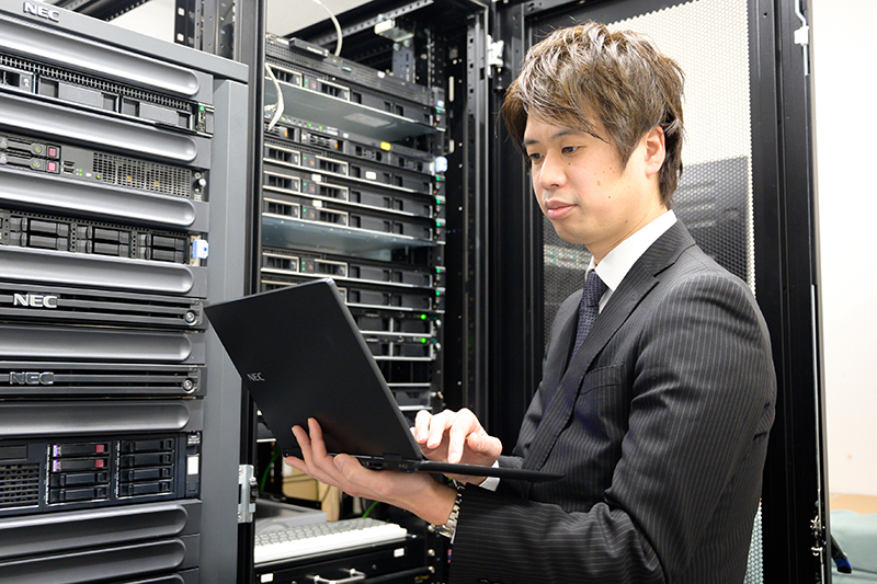 サーバールームでパソコンを操作している男性