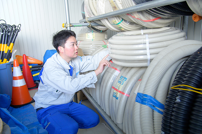 ホース置き場で作業する男性
